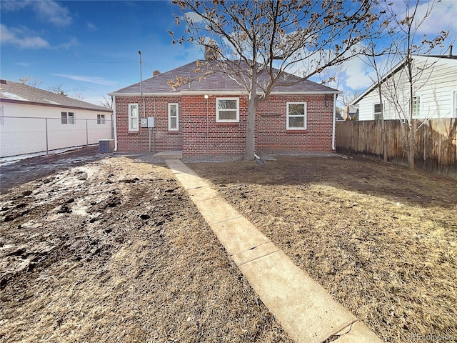 back of property with a fenced backyard, central AC unit, and brick siding