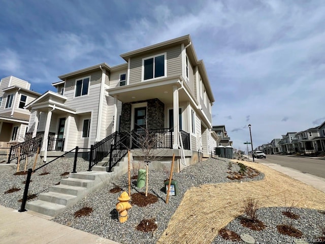 view of front of home featuring a porch, a residential view, and stone siding