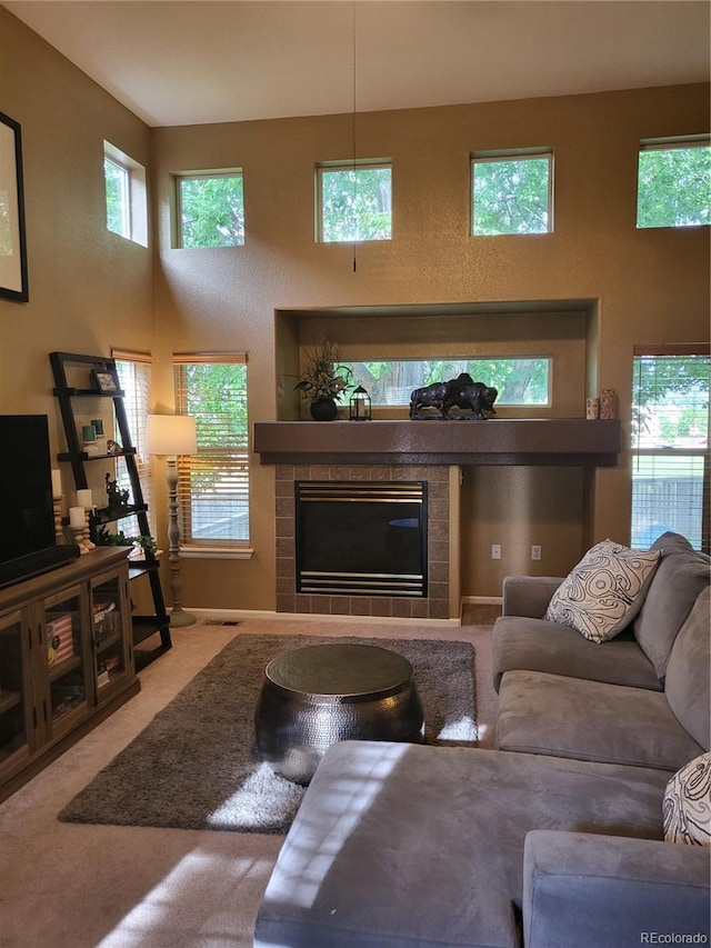10386 Ravenswood Way, Highlands Ranch, CO 80130 - carpeted living area featuring a tile fireplace, plenty of natural light, and a towering ceiling