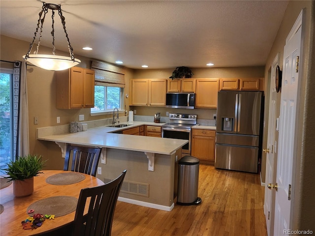 10386 Ravenswood Way, Highlands Ranch, CO 80130 - kitchen with stainless steel appliances, a peninsula, light countertops, light wood-style floors, and recessed lighting