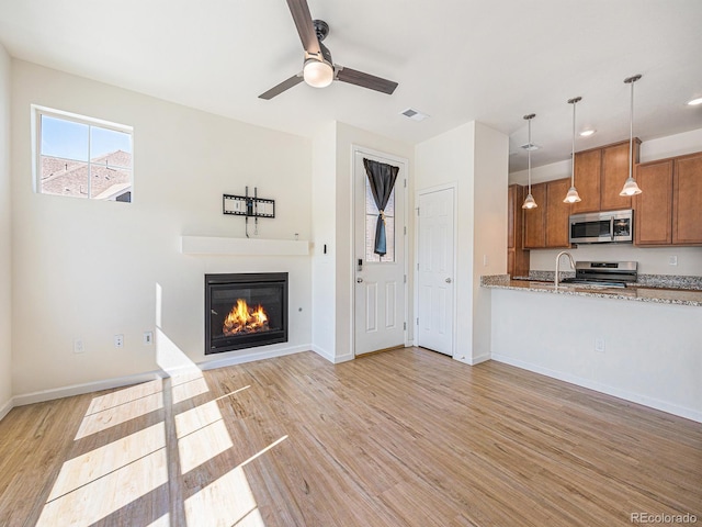 5755 S Buchanan Ct Unit E, Aurora, CO 80016 - unfurnished living room featuring light wood finished floors, a glass covered fireplace, a ceiling fan, and recessed lighting
