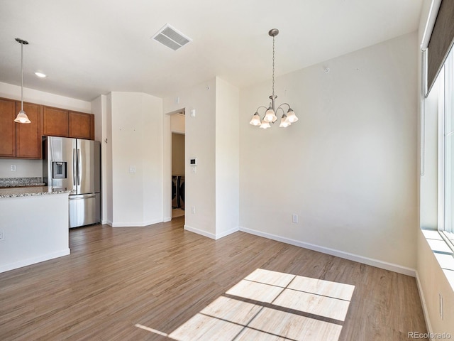 5755 S Buchanan Ct Unit E, Aurora, CO 80016 - kitchen with stainless steel fridge, brown cabinetry, light wood-style flooring, and a chandelier