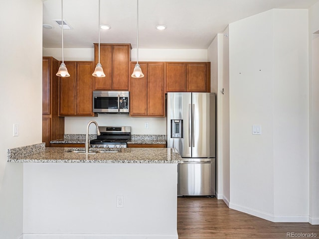 5755 S Buchanan Ct Unit E, Aurora, CO 80016 - kitchen with stainless steel appliances, light stone countertops, brown cabinetry, and dark wood finished floors