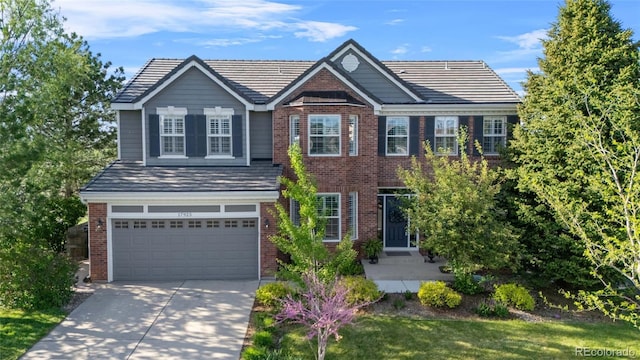 view of front of house featuring brick siding, driveway, an attached garage, and a tile roof