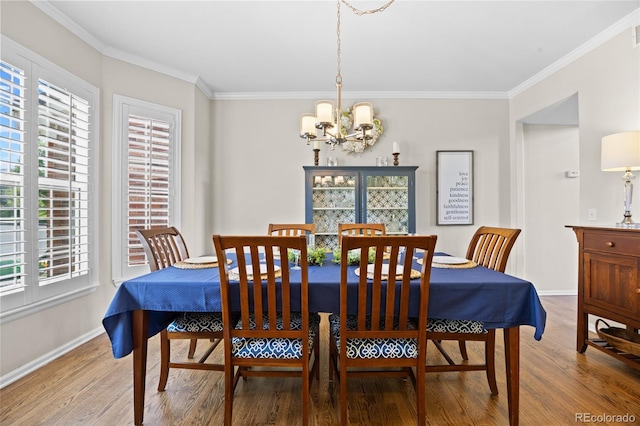 dining space featuring wood finished floors, a chandelier, baseboards, and ornamental molding