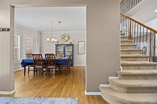 dining room featuring baseboards, stairway, ornamental molding, and wood finished floors