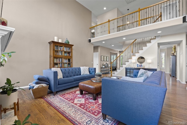 living area featuring wood finished floors, a towering ceiling, stairway, and baseboards