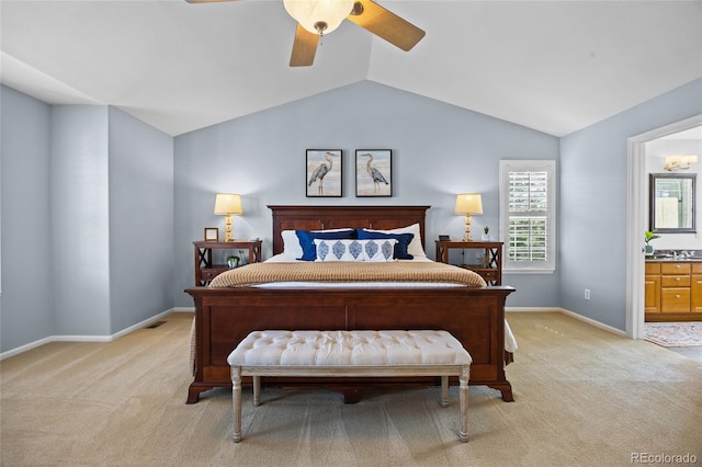 bedroom featuring light carpet, vaulted ceiling, ensuite bathroom, ceiling fan, and baseboards