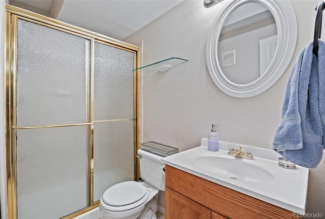 bathroom with a shower stall, toilet, vanity, and a textured wall
