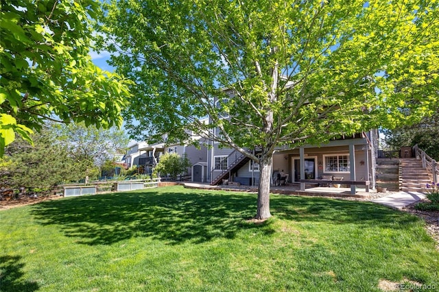 view of green lawn with stairs and a patio area