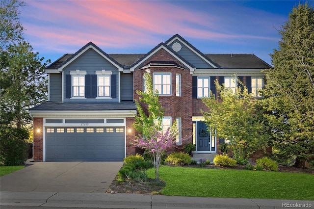 view of front of house with brick siding, driveway, a lawn, and a garage