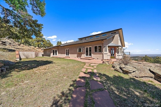 5197 Bear Mountain Dr, Evergreen, CO 80439 - back of property with metal roof, stucco siding, french doors, and a lawn