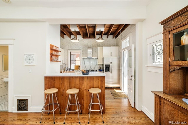 2228 N Race St, Denver, CO 80205 - kitchen featuring stainless steel fridge, light wood finished floors, wall chimney exhaust hood, a peninsula, and a breakfast bar