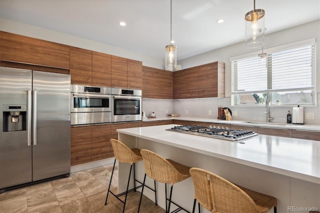 kitchen featuring pendant lighting, sink, a breakfast bar area, stainless steel appliances, and decorative backsplash