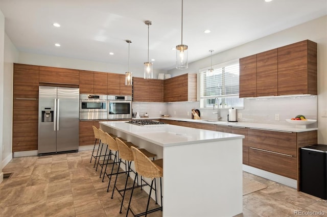 kitchen featuring a kitchen bar, sink, a kitchen island, stainless steel appliances, and backsplash