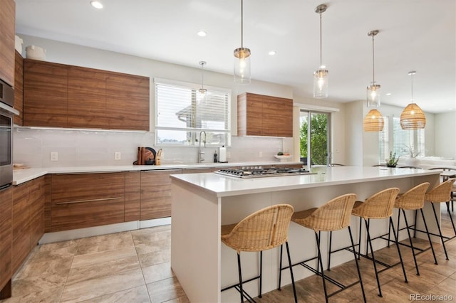 kitchen featuring a kitchen island, stainless steel gas stovetop, tasteful backsplash, sink, and a breakfast bar area