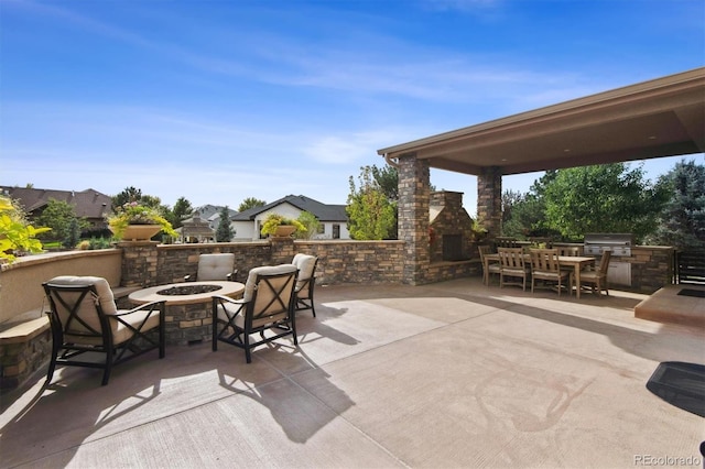 view of patio / terrace featuring a grill, a fire pit, an outdoor stone fireplace, and an outdoor kitchen