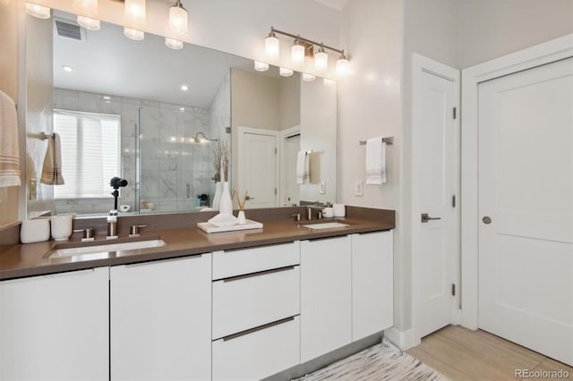 bathroom with walk in shower, vanity, and hardwood / wood-style flooring