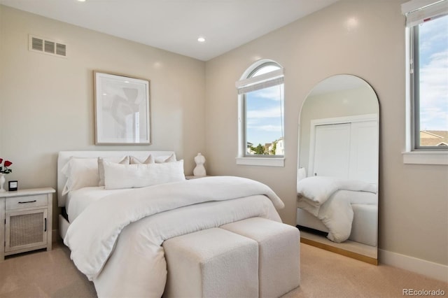 bedroom featuring light colored carpet, a closet, and multiple windows