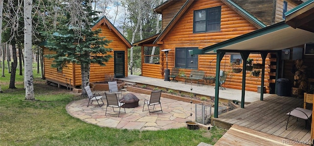 back of property featuring a wooden deck, a patio, and an outdoor fire pit