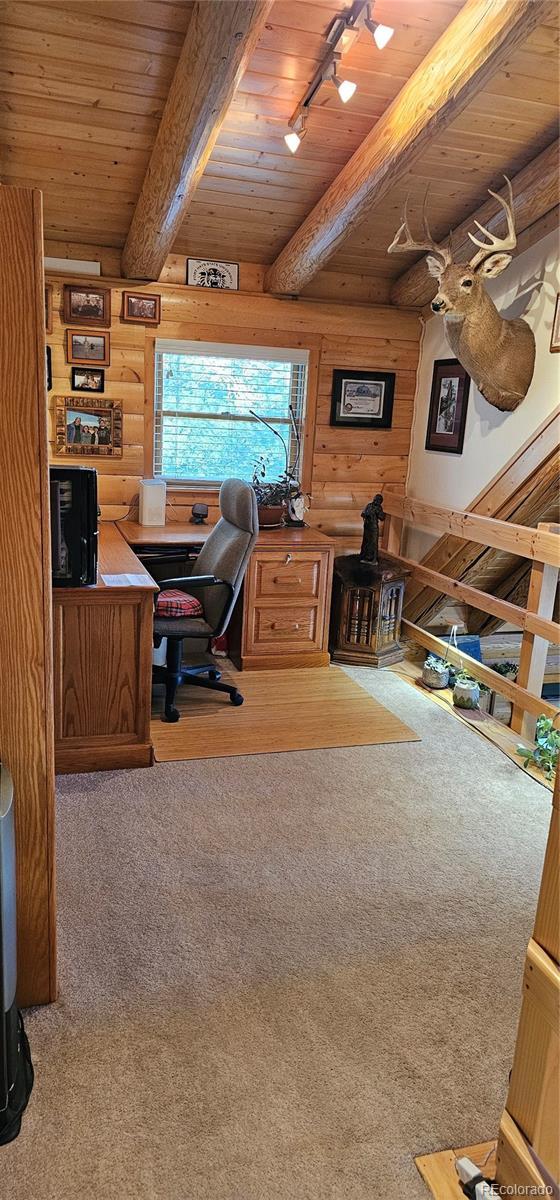 home office with rustic walls, wooden ceiling, carpet, and beam ceiling