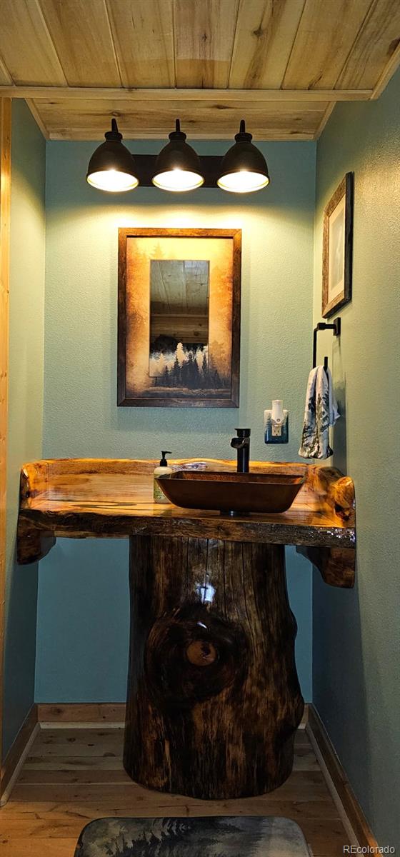 bathroom with a sink, wooden ceiling, baseboards, and wood finished floors