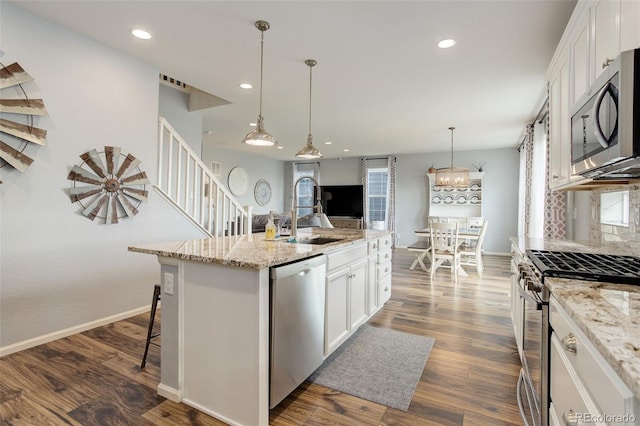 11038 Unity Ln, Commerce City, CO 80022 - kitchen with stainless steel appliances, white cabinets, recessed lighting, a kitchen island with sink, and a breakfast bar area