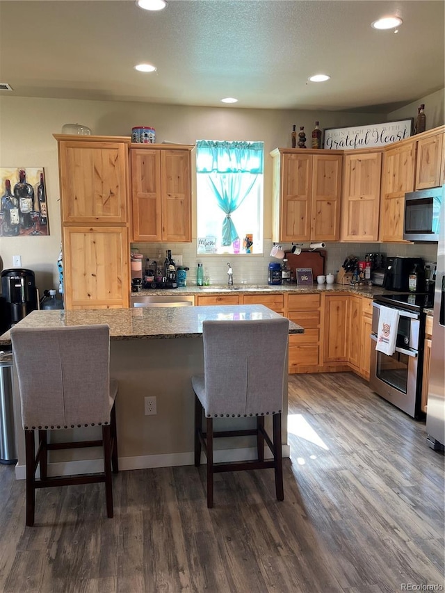 3892 Hackberry St, Wellington, CO 80549 - kitchen with stainless steel appliances, a kitchen breakfast bar, recessed lighting, dark wood-type flooring, and backsplash