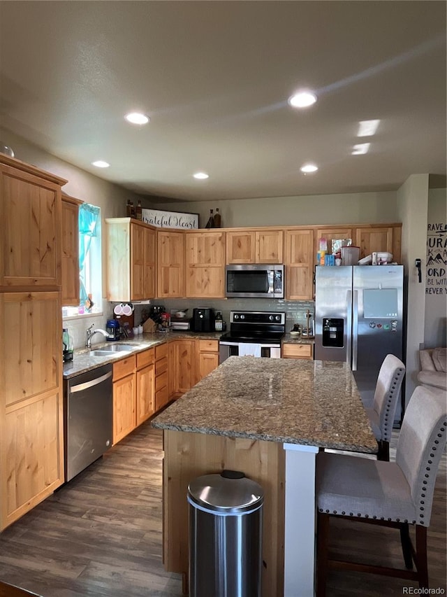 3892 Hackberry St, Wellington, CO 80549 - kitchen with stainless steel appliances, dark wood-style flooring, a center island, a kitchen breakfast bar, and dark stone countertops