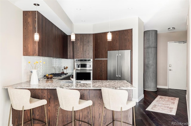 kitchen featuring tasteful backsplash, dark brown cabinets, a peninsula, stainless steel appliances, and modern cabinets