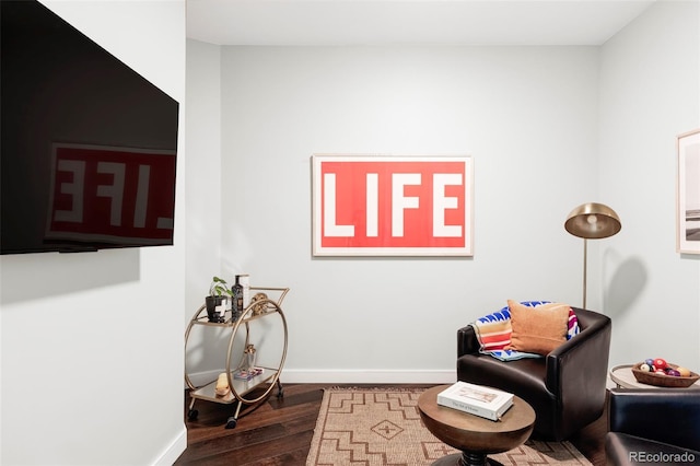 living area with baseboards and dark wood-type flooring