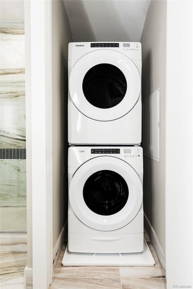 washroom featuring baseboards, laundry area, and stacked washer / dryer