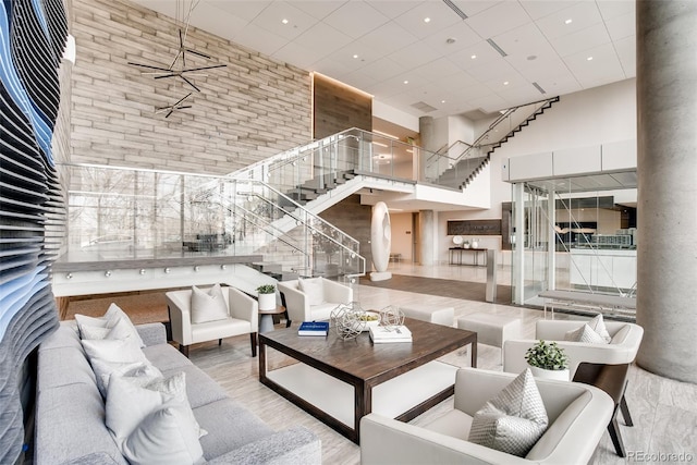 living area with stairs, a high ceiling, wood finished floors, and ceiling fan