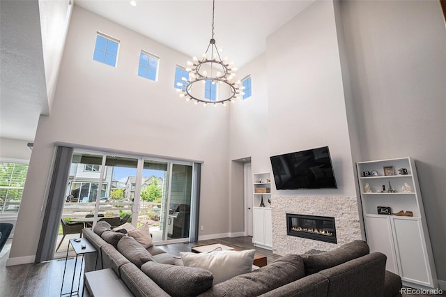 9380 Bear River St, Littleton, CO 80125 - living area featuring dark wood-style flooring, a chandelier, a high ceiling, baseboards, and a glass covered fireplace