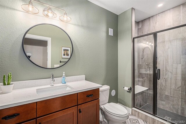 9380 Bear River St, Littleton, CO 80125 - full bathroom with toilet, vanity, a shower stall, and a textured wall