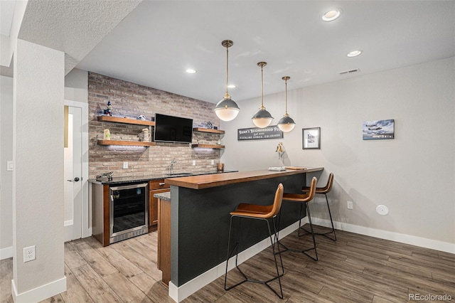 9380 Bear River St, Littleton, CO 80125 - indoor wet bar with wine cooler, light wood finished floors, baseboards, recessed lighting, and decorative light fixtures