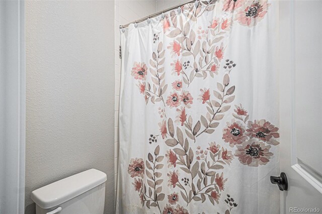 9380 Bear River St, Littleton, CO 80125 - bathroom featuring toilet, a textured wall, and curtained shower