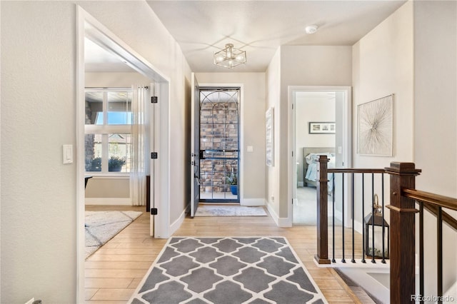 entryway with light wood-style flooring, a chandelier, and baseboards