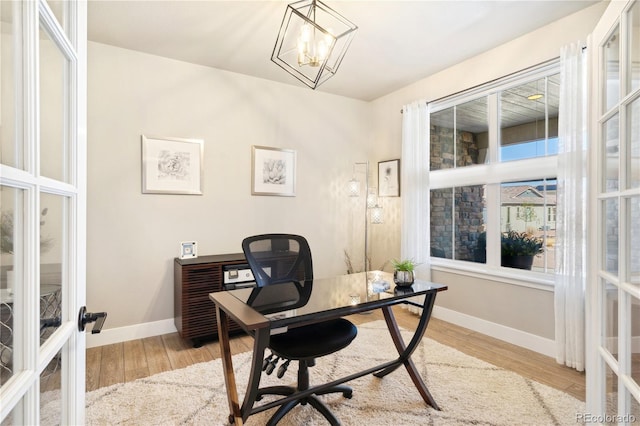 home office featuring french doors, baseboards, light wood-type flooring, and a chandelier