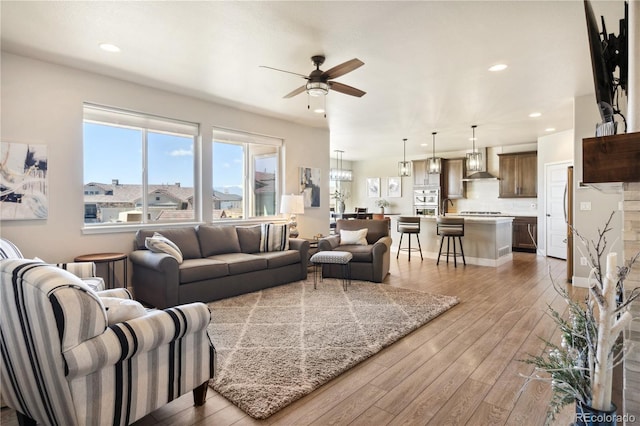 living room with a ceiling fan, light wood-style floors, and recessed lighting