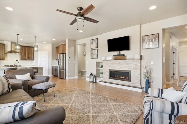 living room with ceiling fan, light wood finished floors, recessed lighting, baseboards, and a fireplace