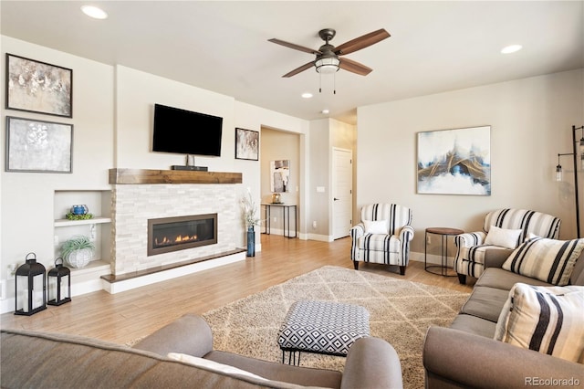 living area featuring a ceiling fan, wood finished floors, a glass covered fireplace, and recessed lighting