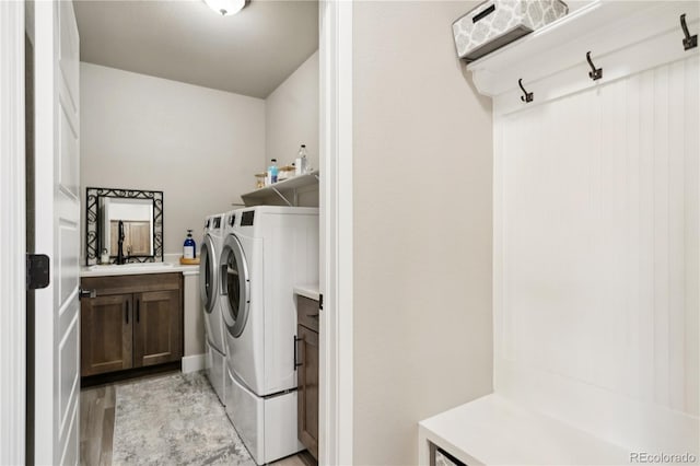 washroom with washing machine and dryer, cabinet space, and light wood-style flooring