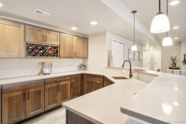 kitchen with a sink, recessed lighting, light countertops, and decorative light fixtures