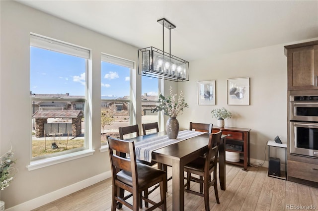 dining room featuring baseboards, light wood-style floors, and a chandelier