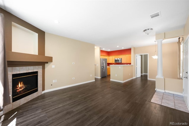 4064 S Carson St Unit 101, Aurora, CO 80014 - unfurnished living room with dark wood-style floors, a tiled fireplace, recessed lighting, and decorative columns