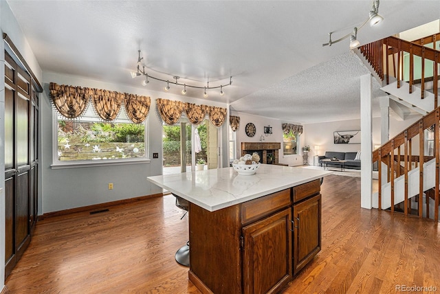 8002 Field Ct, Arvada, CO 80005 - kitchen featuring dark wood-type flooring, a fireplace, a kitchen island, a textured ceiling, and open floor plan