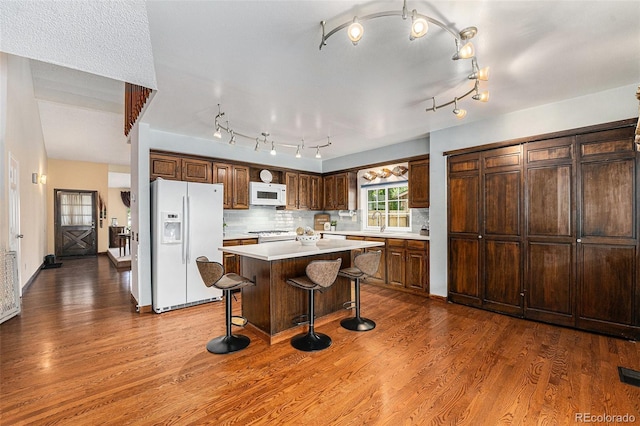 8002 Field Ct, Arvada, CO 80005 - kitchen featuring white appliances, dark wood finished floors, light countertops, and a breakfast bar area