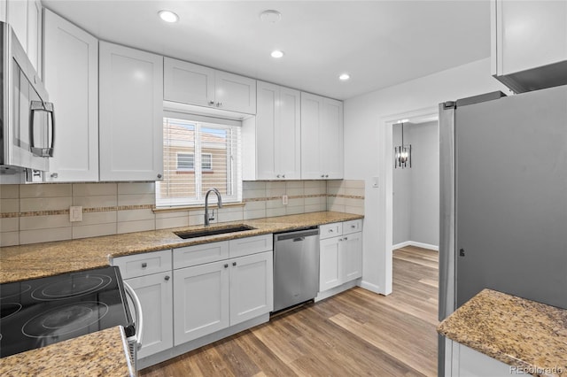 2582 S Uno Way, Denver, CO 80219 - kitchen with stainless steel appliances, white cabinets, light wood-style floors, backsplash, and recessed lighting