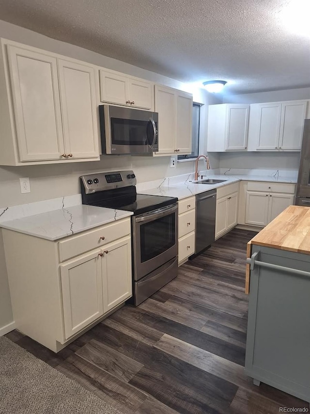 6207 W 92nd Pl, Westminster, CO 80031 - kitchen with appliances with stainless steel finishes, dark wood-type flooring, white cabinets, a textured ceiling, and butcher block counters